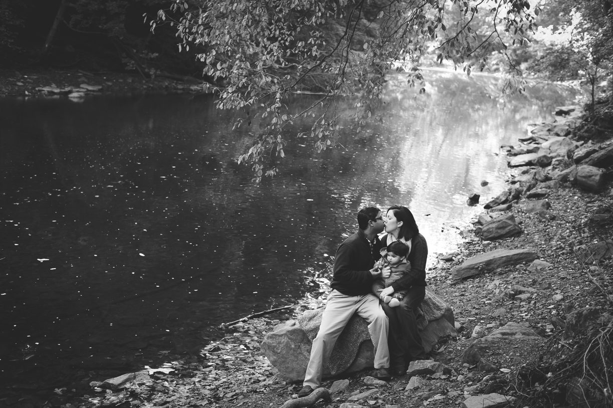 family sitting on rock near a stream