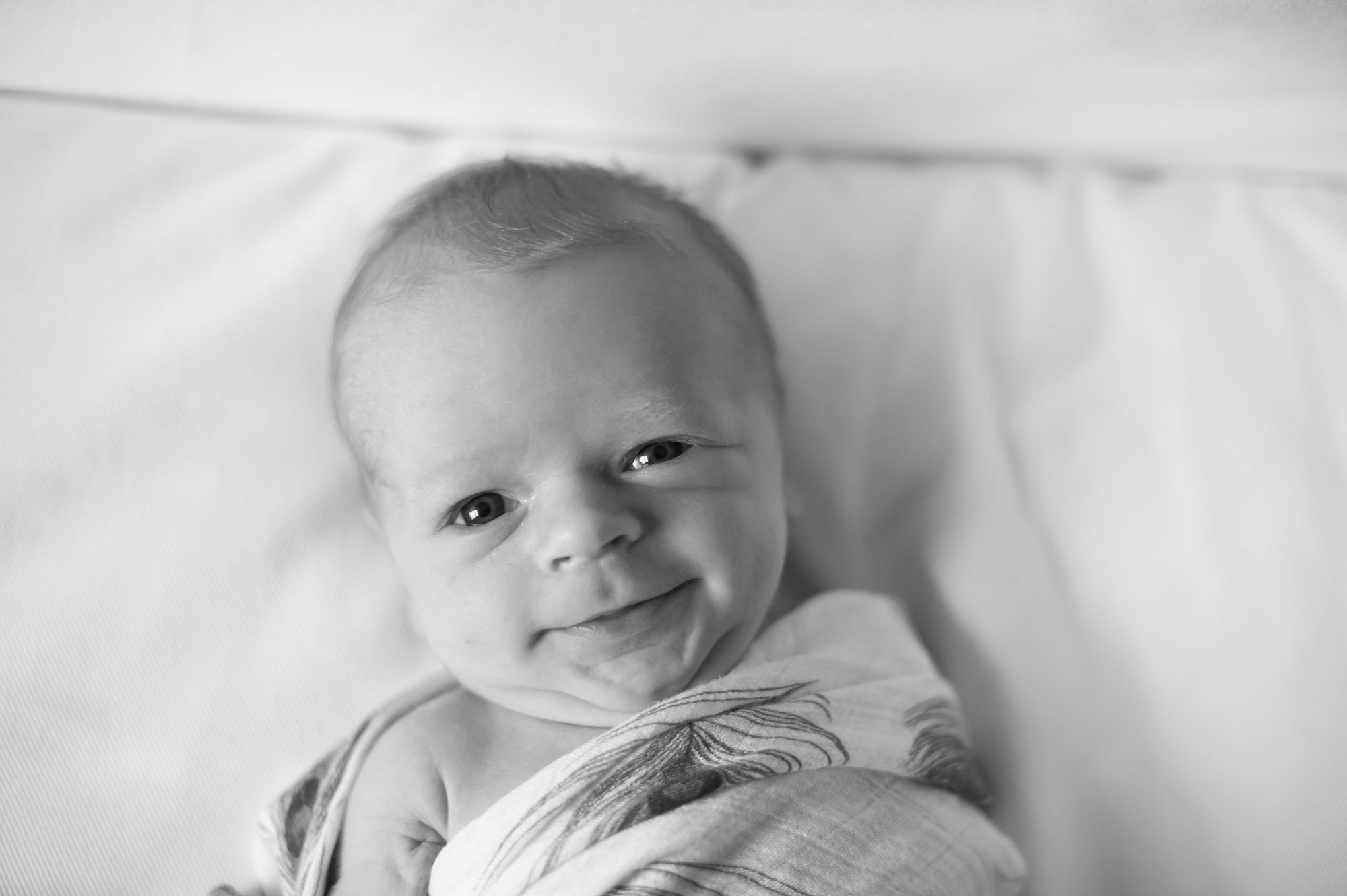 baby smiling wrapped in a blanket at in-home Philadelphia newborn photography session