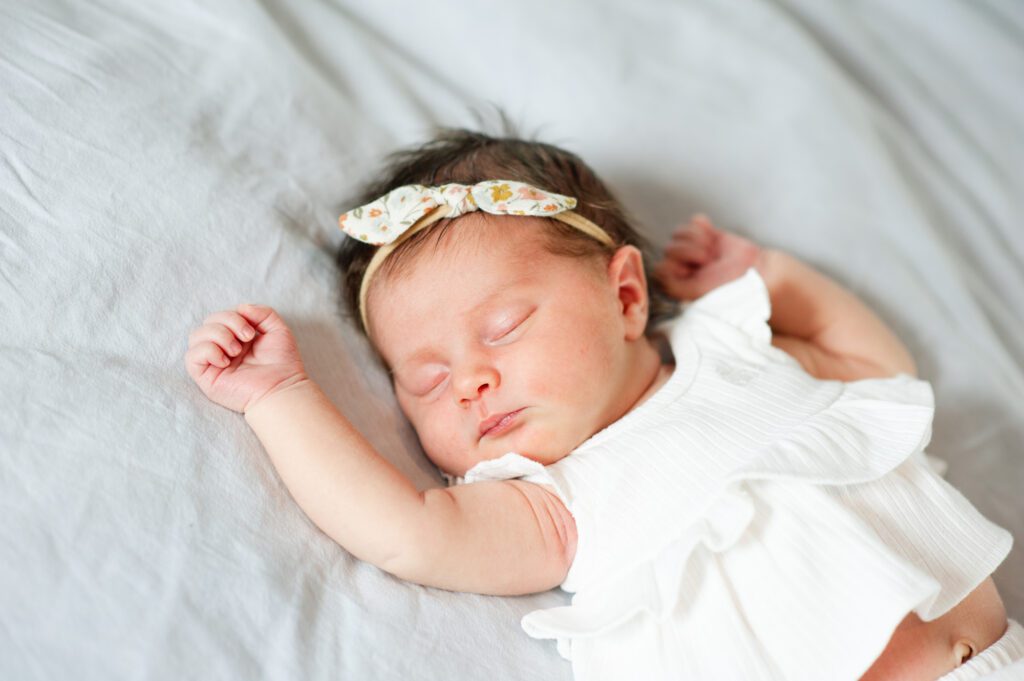 newborn baby laying on a white bed