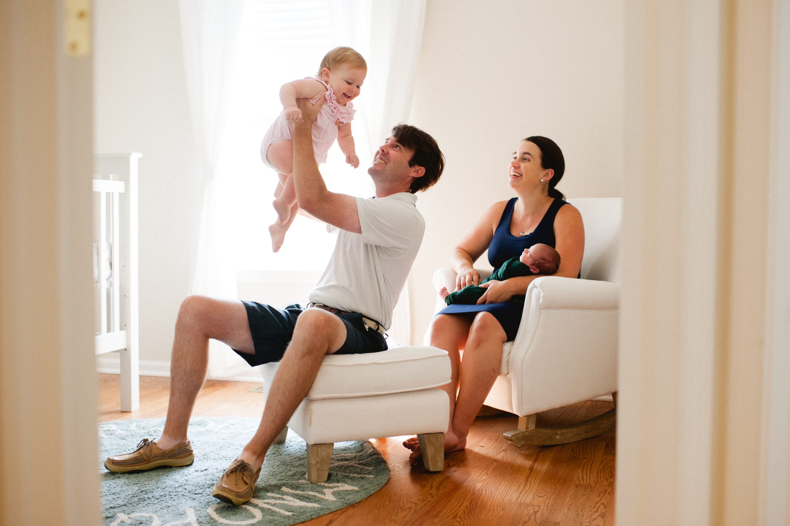 dad holds his daughter and mom holds her son while sitting in a nursery at an in-home Philadelphia newborn session