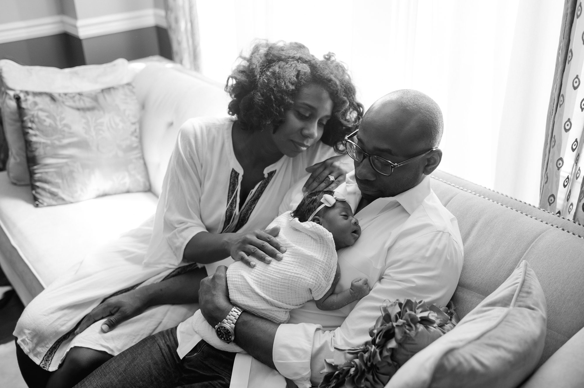 Philadelphia newborn photography session in-home with a couple sitting on their couch holding their newborn